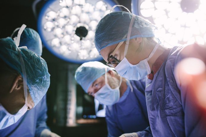 Concentrated surgeon performing surgery with her team
